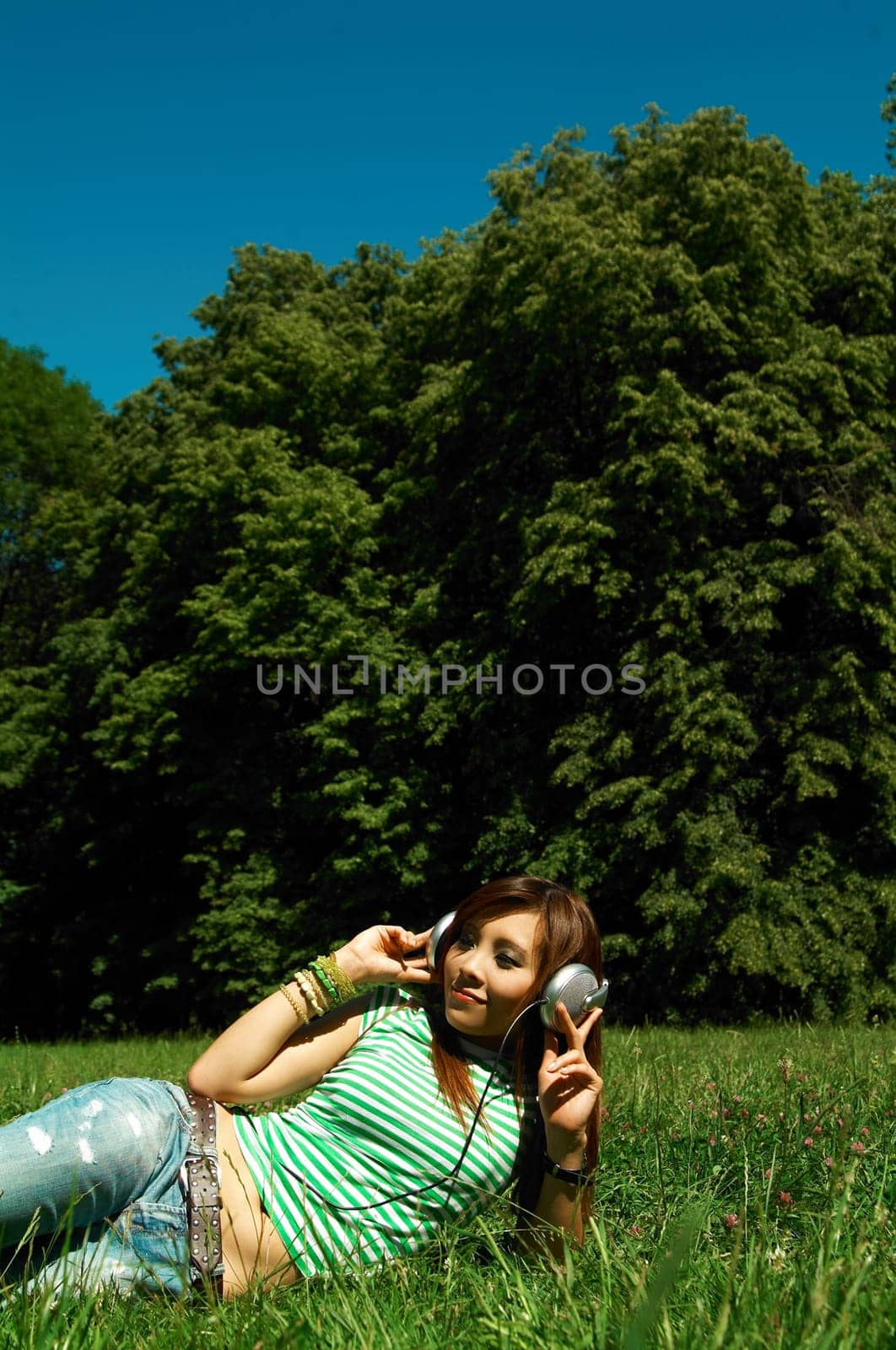 Beautiful asian young girl with headphones, listen to music on meadow