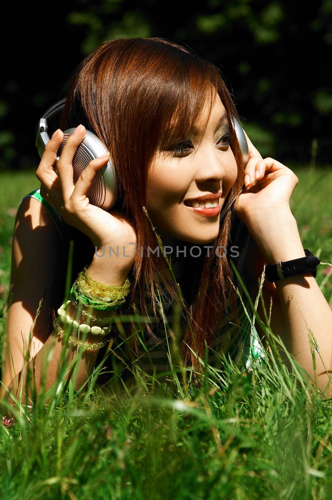 Beautiful asian young girl with headphones, listen to music on meadow