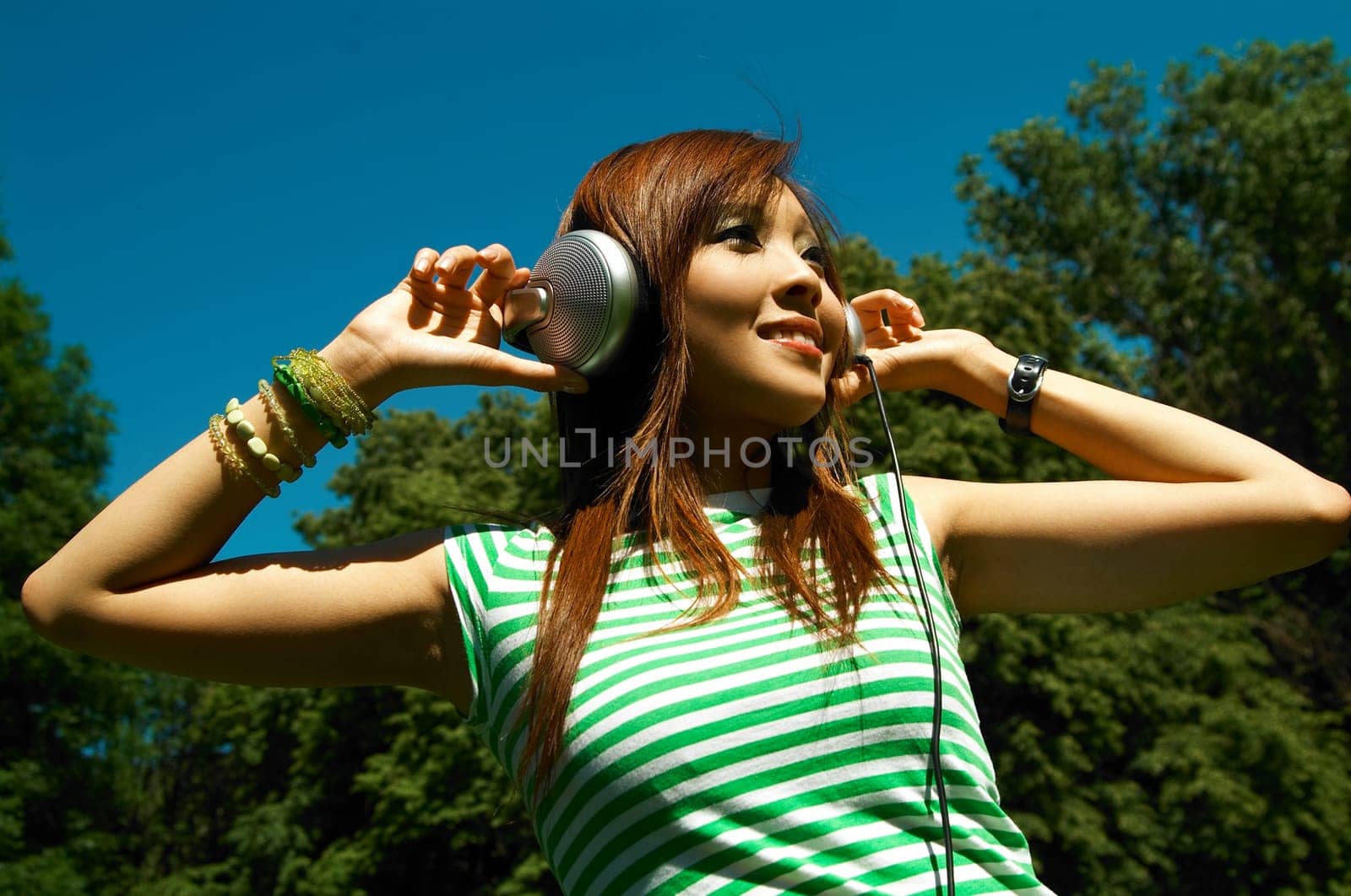 Beautiful asian young girl with headphones, listen to music on meadow