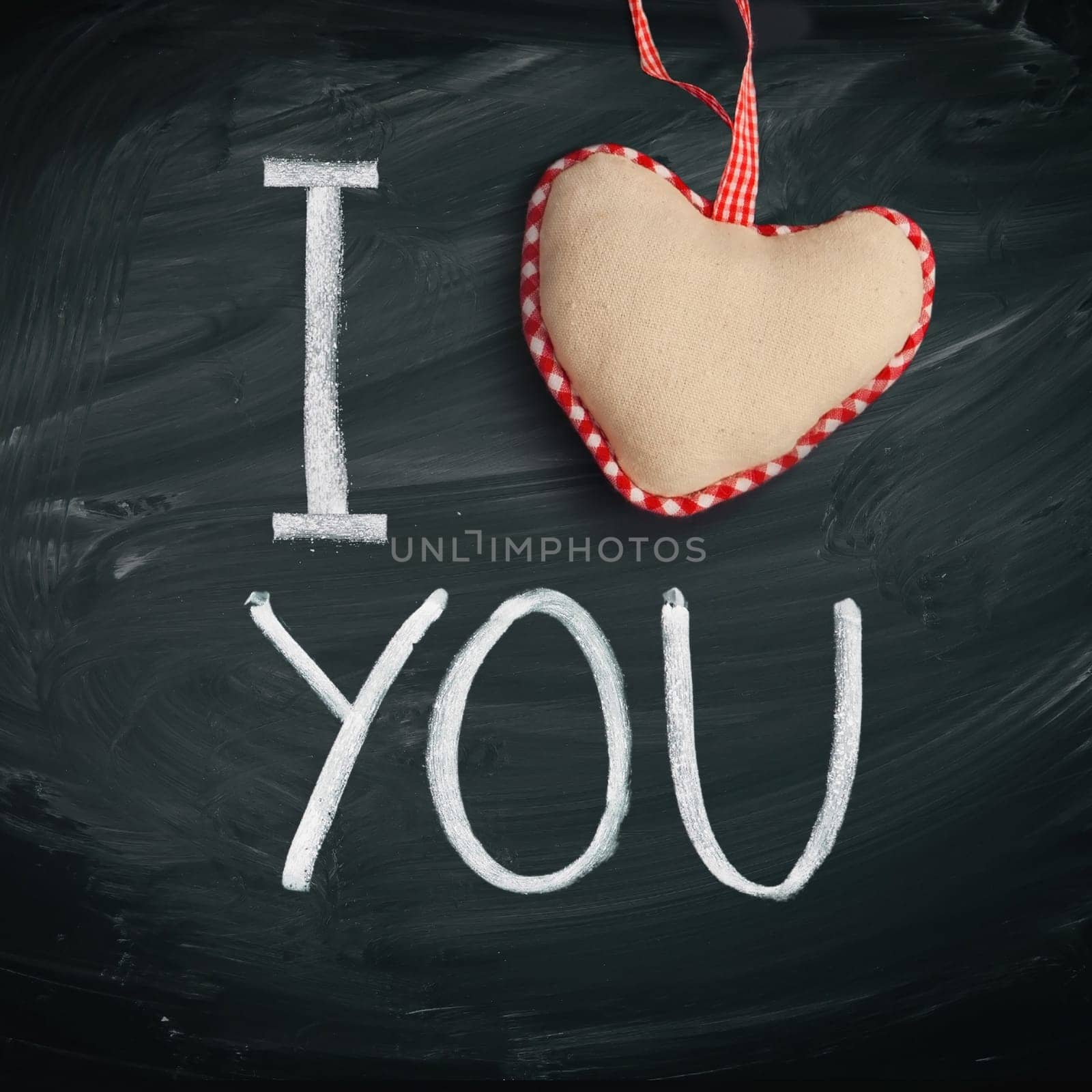 I Love You. Handwritten message on a chalkboard with a rustic needlework heart used as a symbol of love in this Valentines message.
