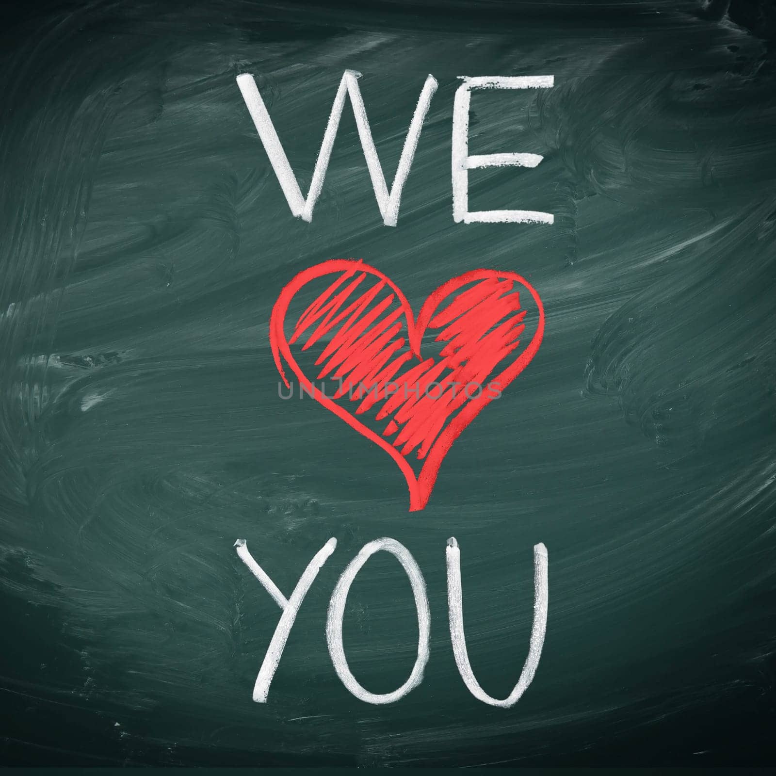We Love You. Handwriiten message in chalk on a blackboard incorporating a red heart symbol for love.