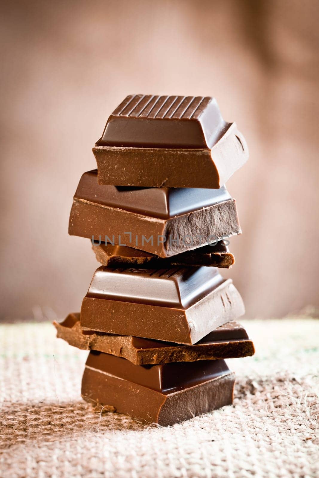 Tower composed of pieces of staple chocolate on a linen background for chocolate and cocoa concepts.