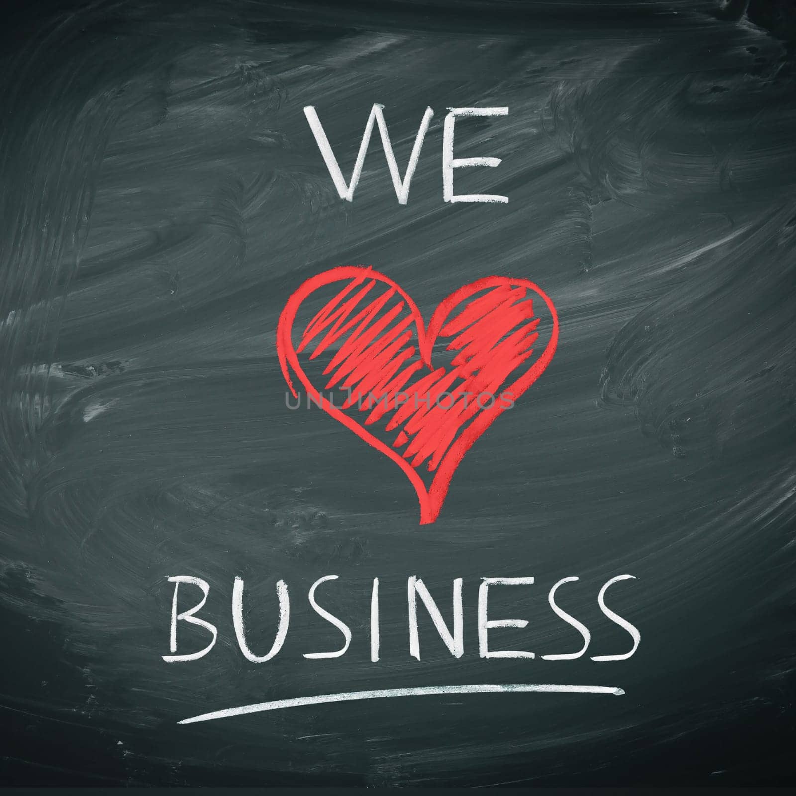 We Love Business. Handwriiten message in chalk on a blackboard incorporating a red heart symbol for love.