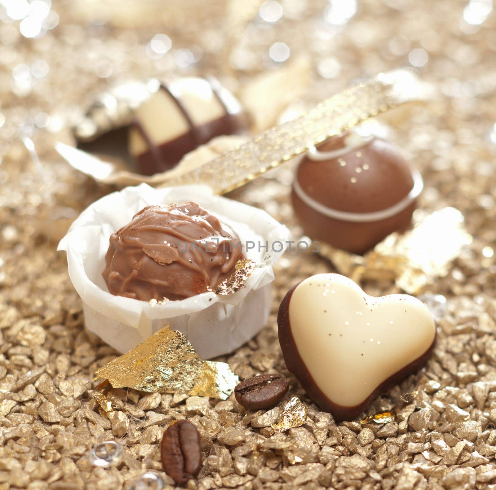 Handmade luxury chocolates with focus to a chocolate heart truffle in the foreground for a celebration, valentines or anniversary