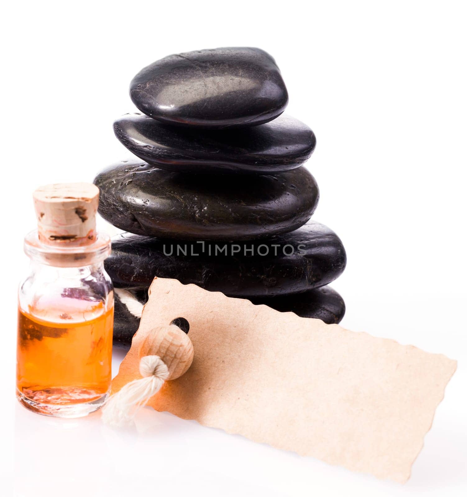 Gift of an aromatherapy massage with a luxury blank gift label in front of massage stonese and a glass bottle of essential oil