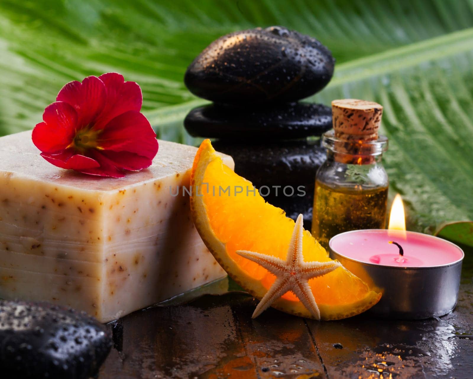 Cheese block and orange slice resting on a table with basalt stones and oils for a spa break