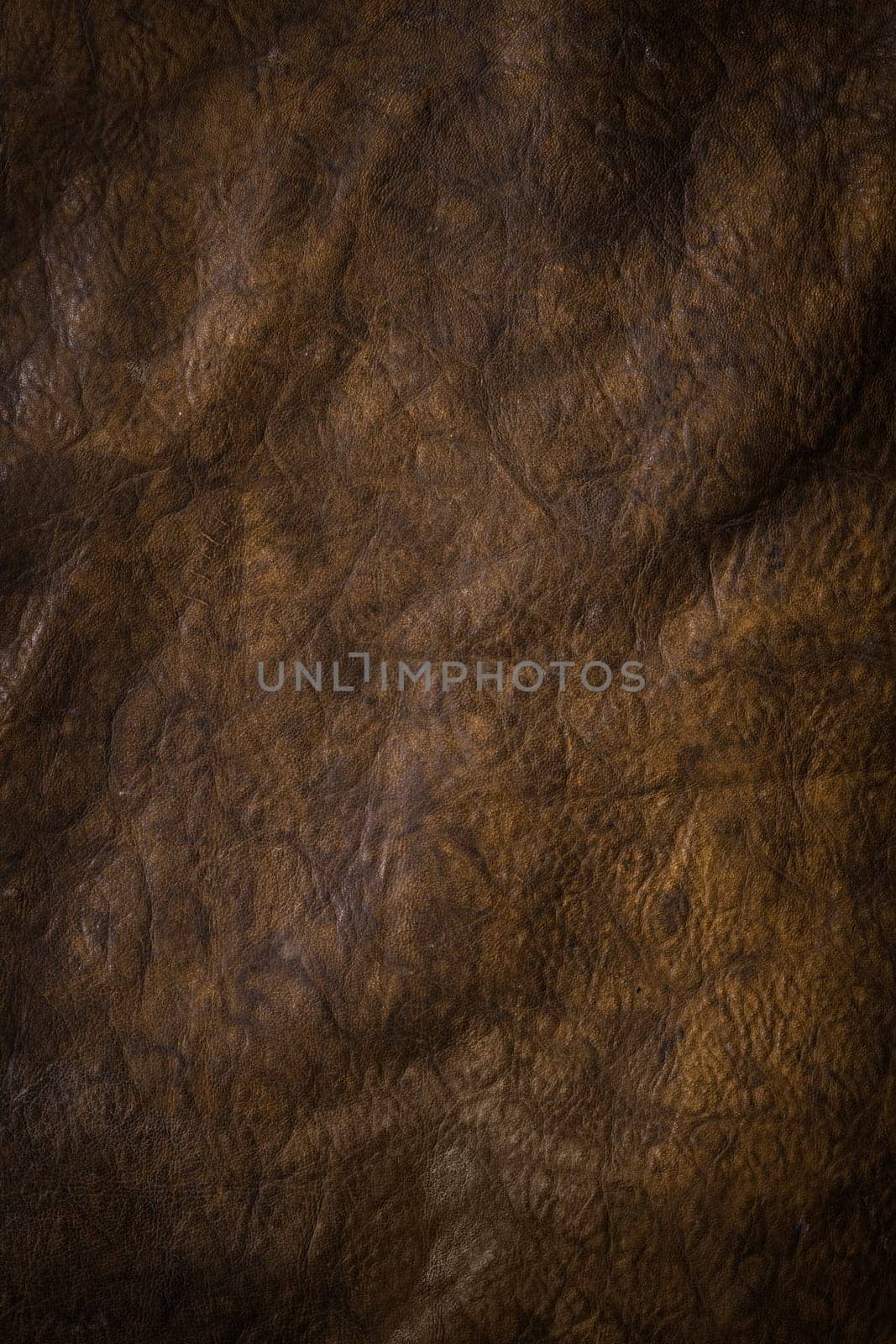 Abstract background of dark brown puckered leather with a rough wrinkled texture and shadowing
