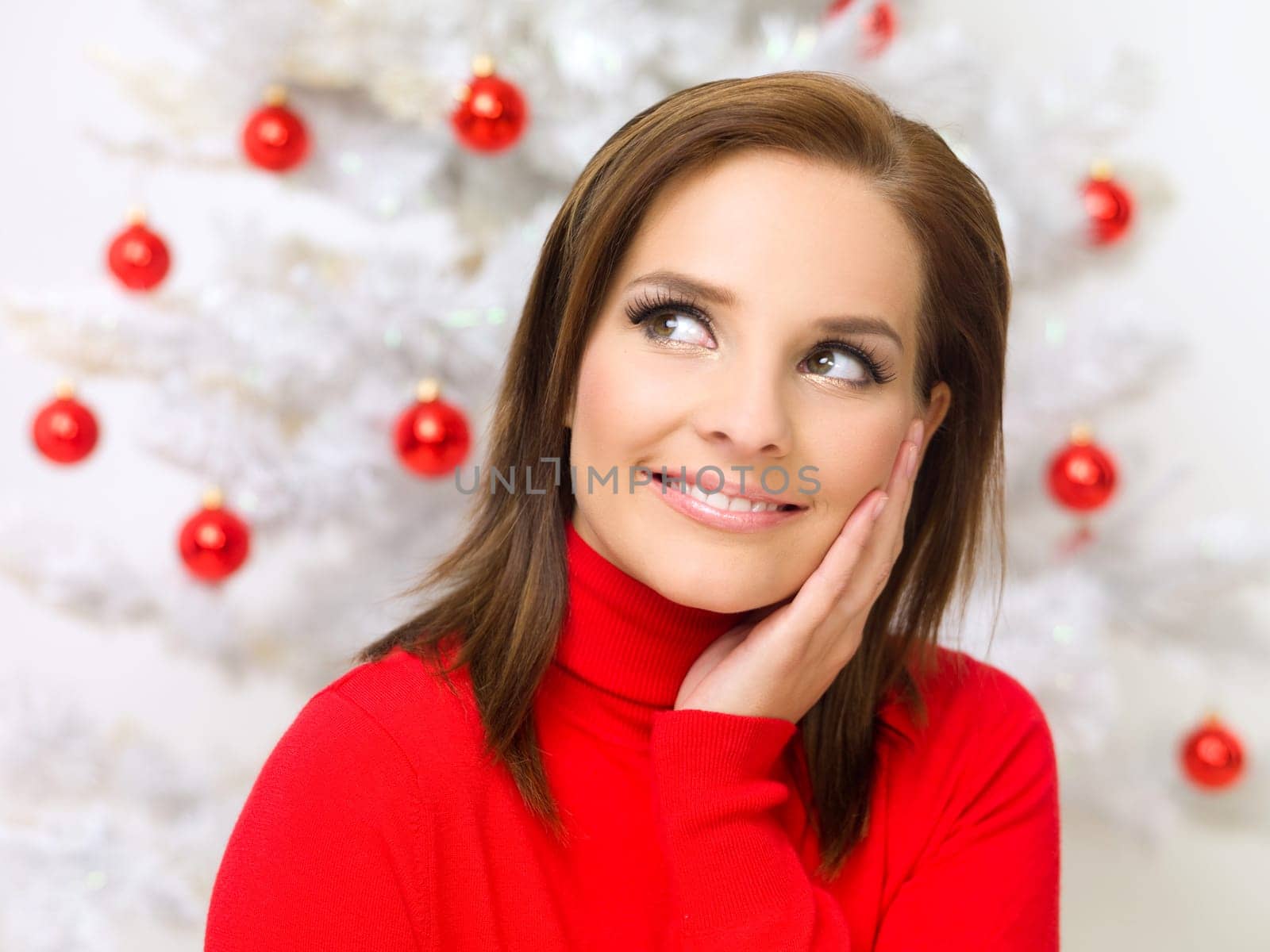 Beautiful woman next to christmas tree wearing red sweater