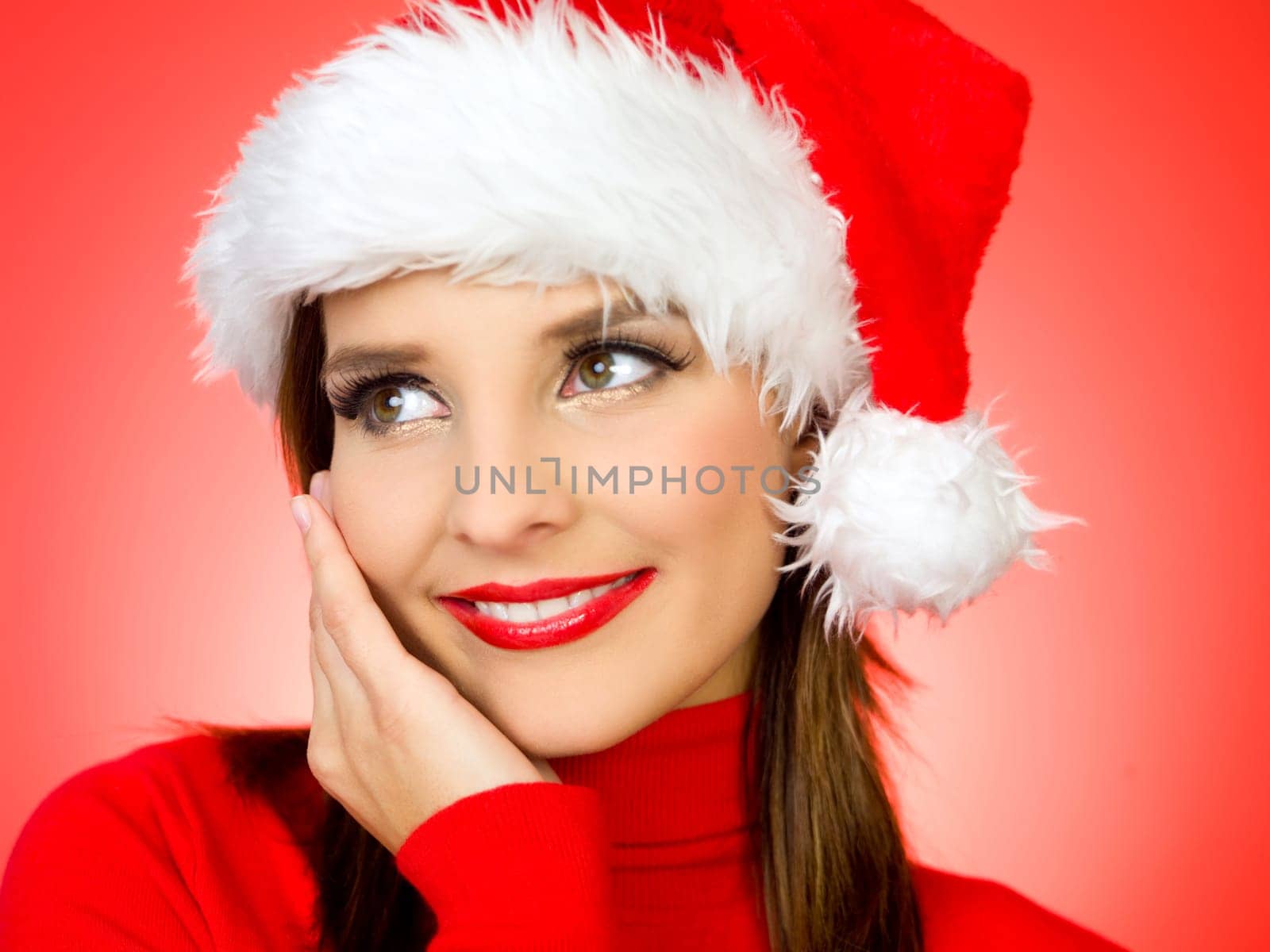 Portrait of beautiful woman wearing santa claus hat on red background