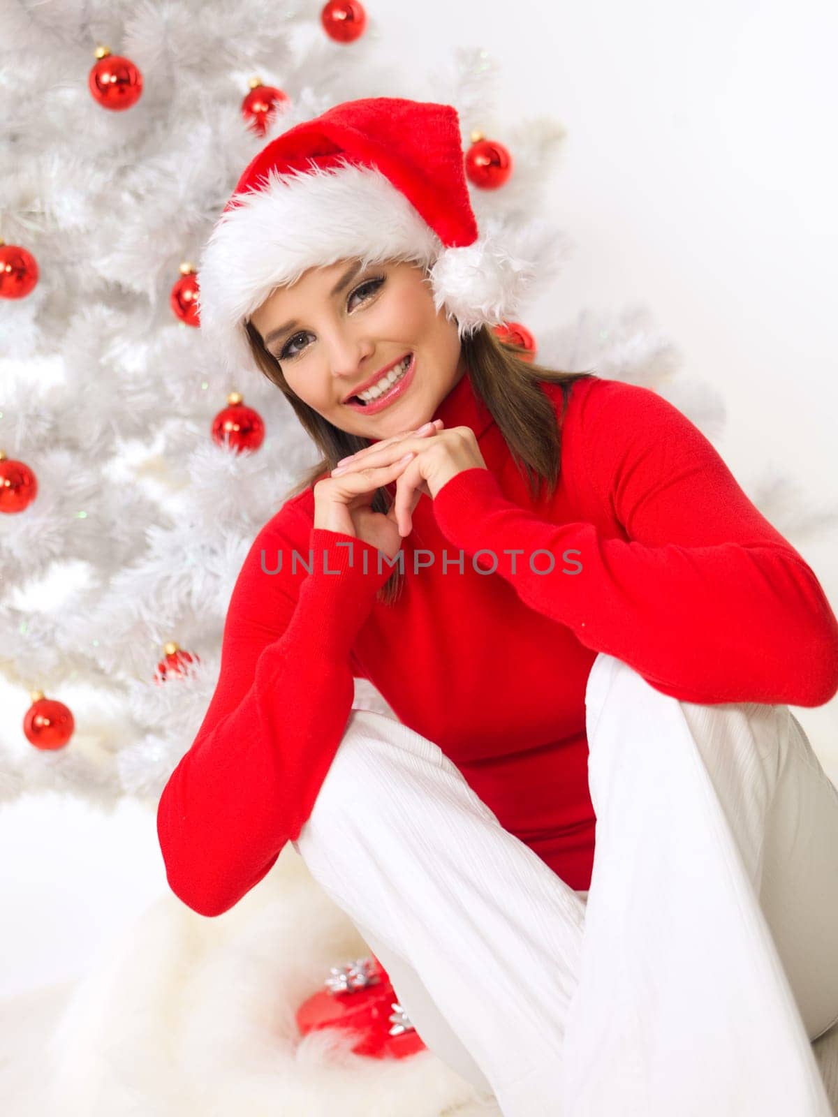 Beautiful woman next to christmas tree wearing red sweater