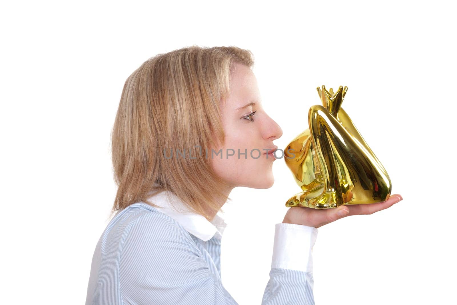 Young blonde woman holding a golden frog in her hand and wants to kiss them