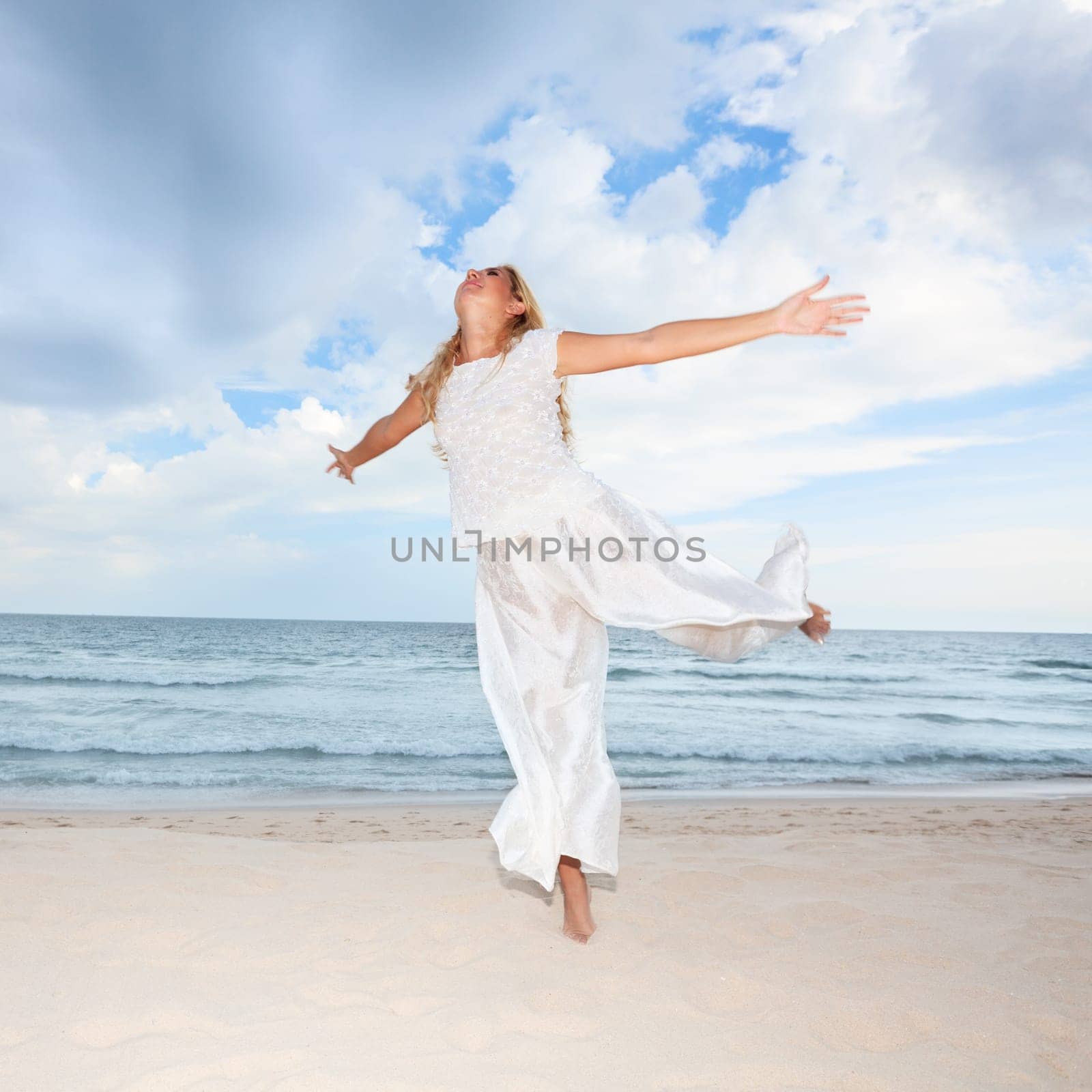 Young woman in white dancing on the beach