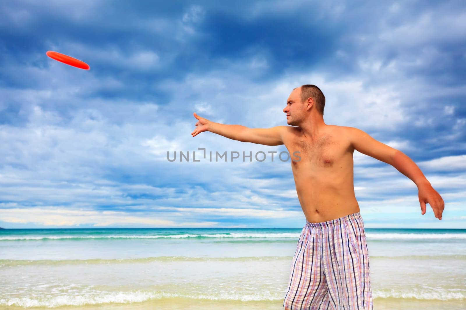 Young man is tossing a frisbee on the beach