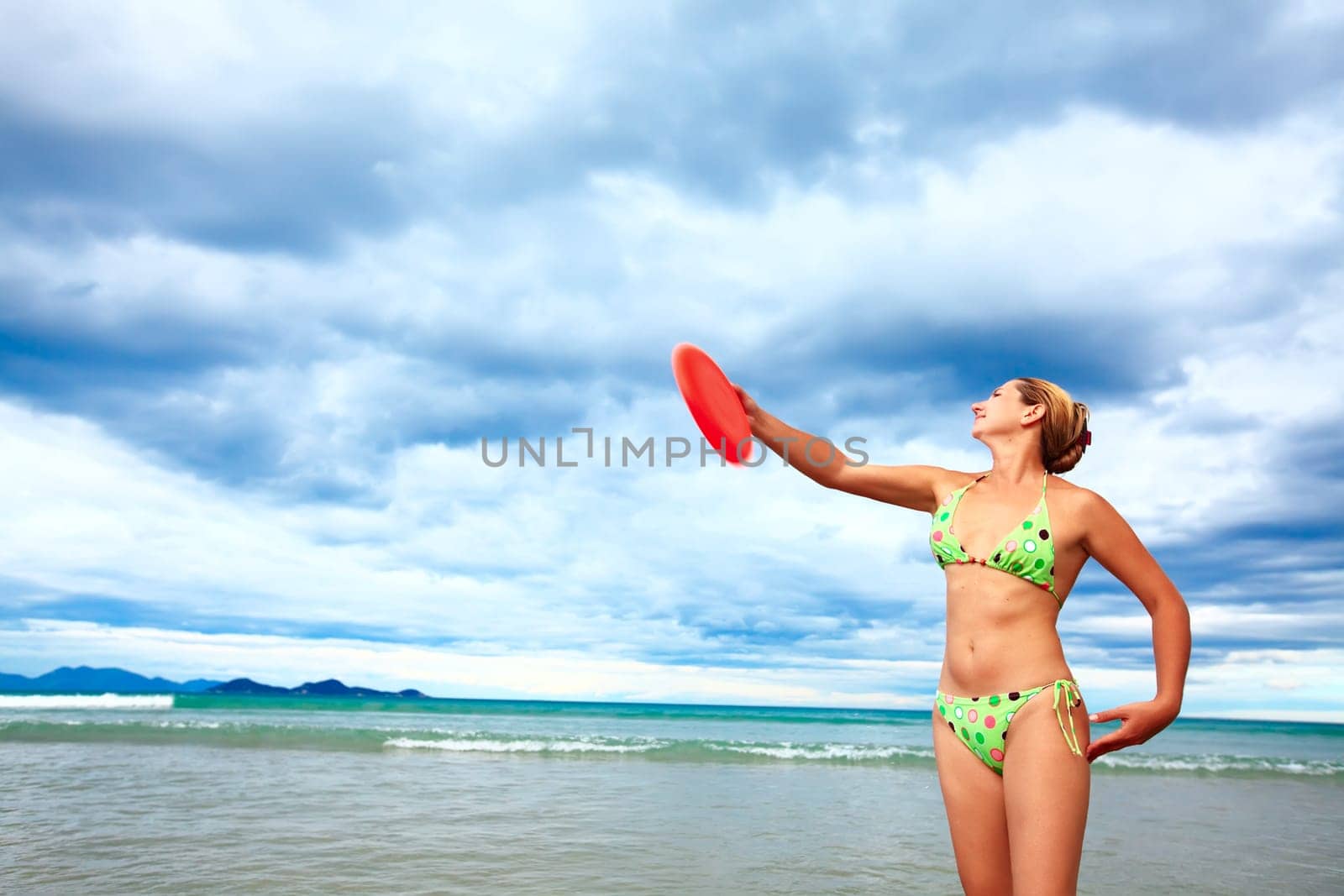 Young woman is tossing a frisbee on the beach