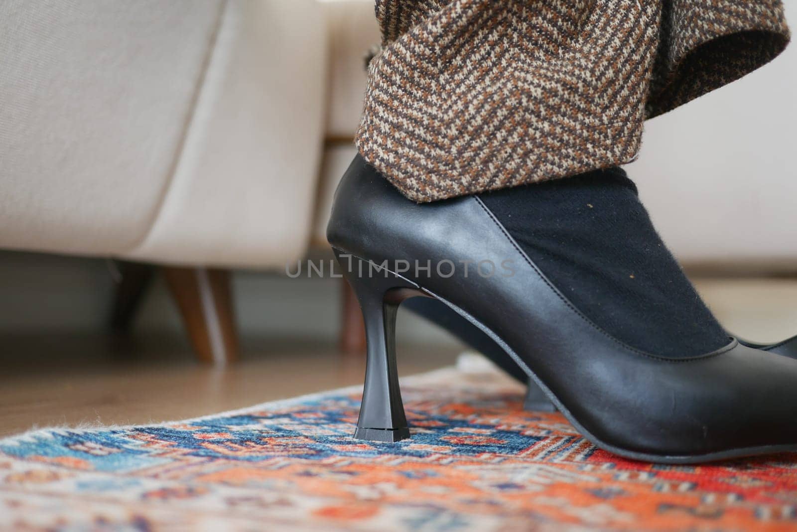 A close-up view of elegant high heels atop a vibrant patterned rug.