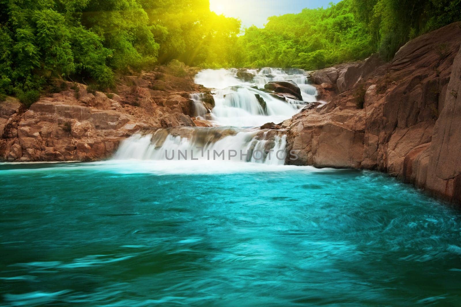 Waterfall pool in rain forest and sunlight