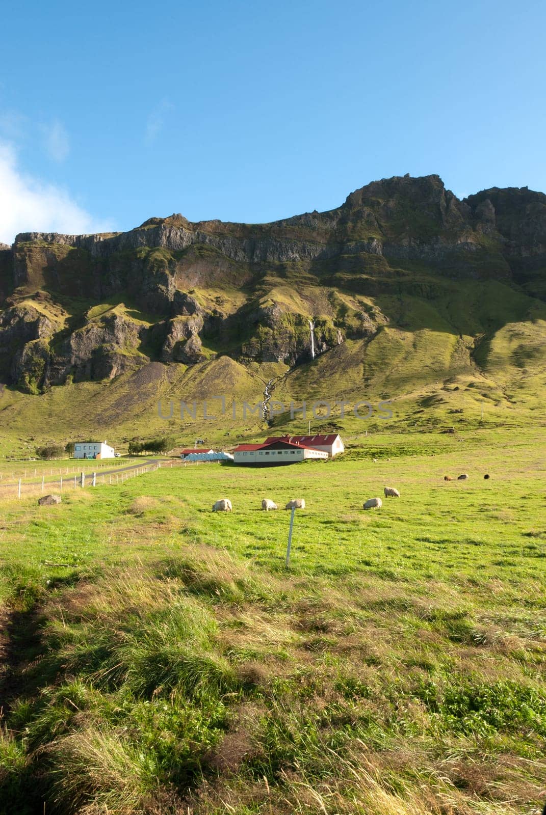 farm and waterfall in the mountains of Iceland