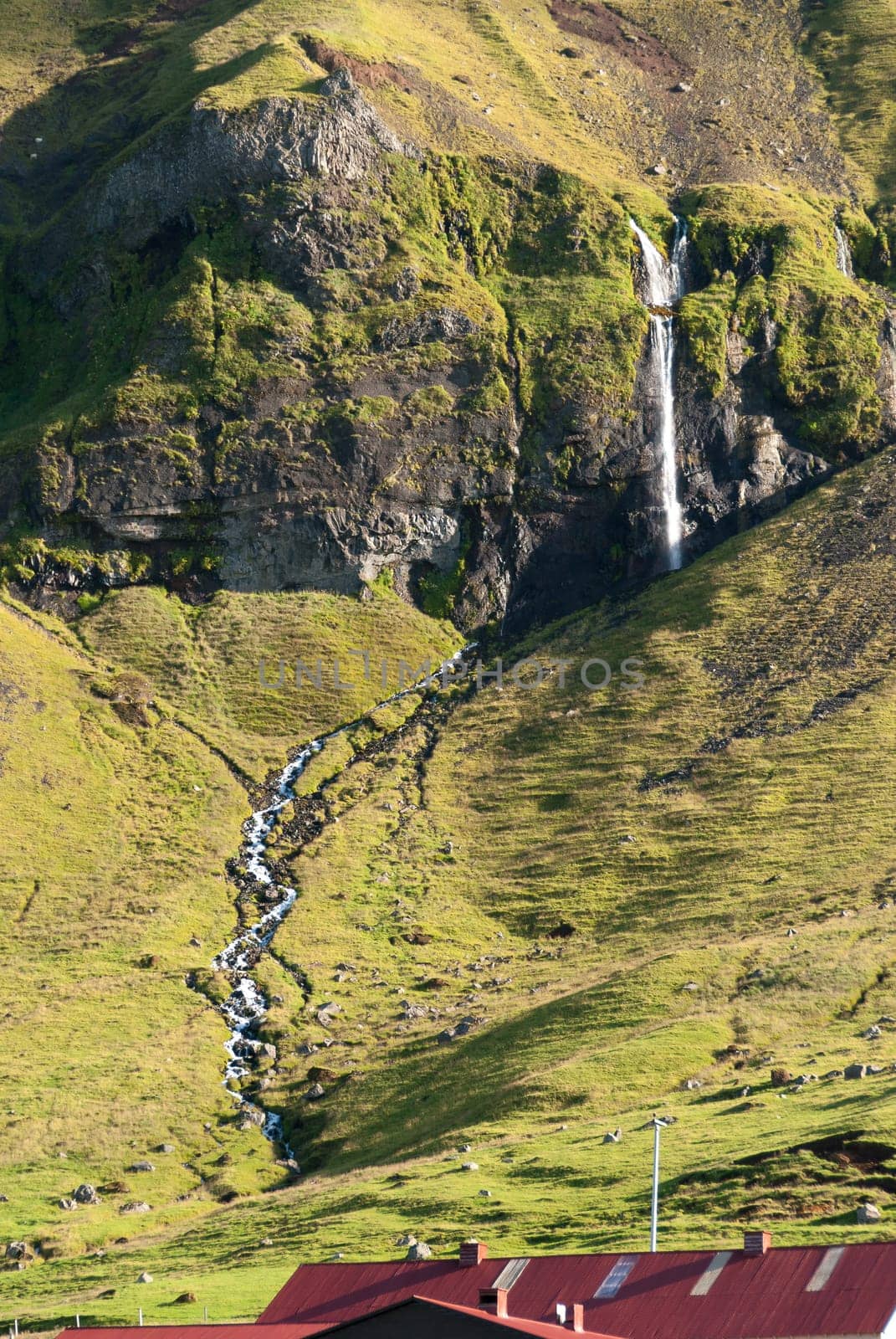 farm and waterfall in the mountains of Iceland