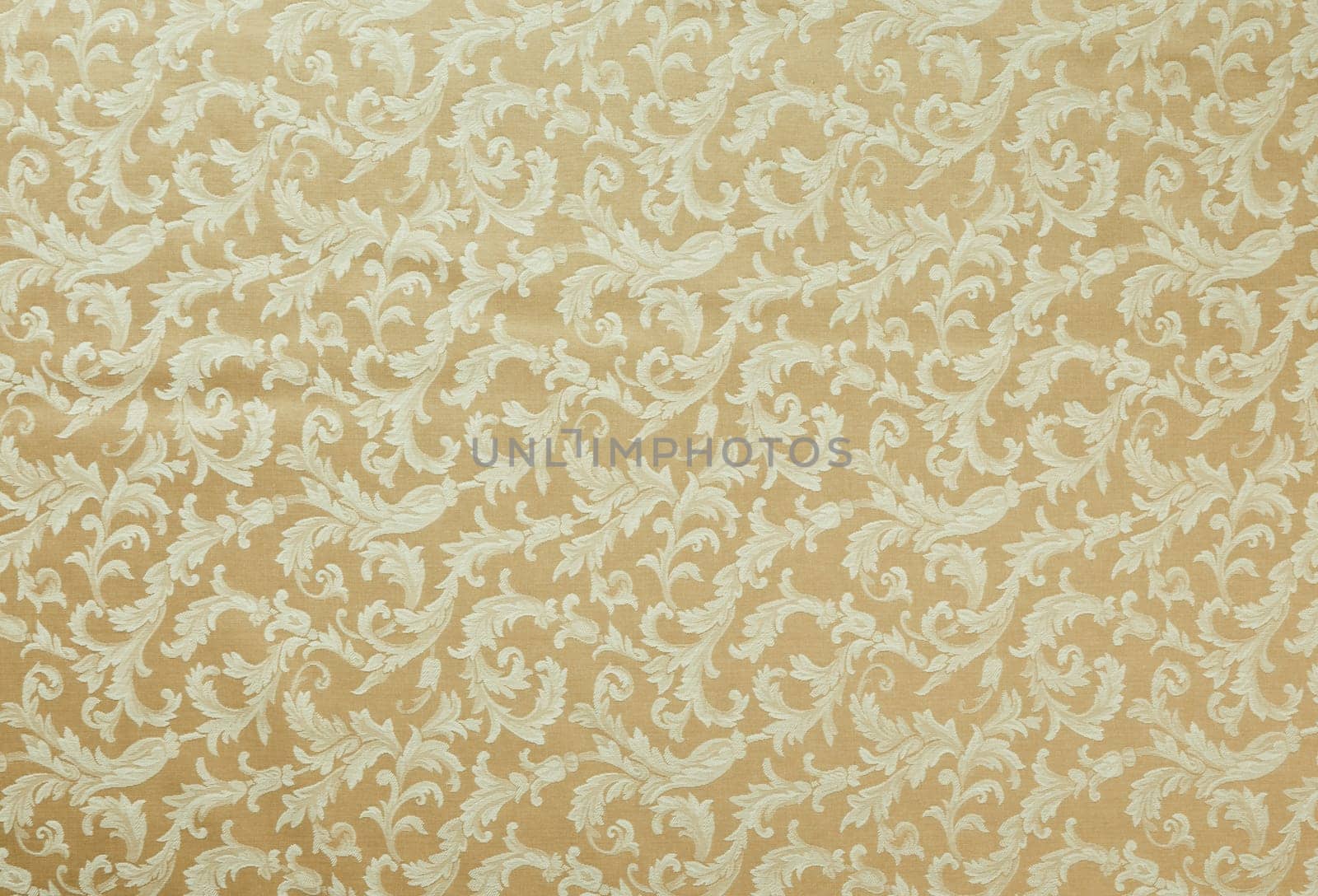 Abstract background of a heavy beige brocade fabric with interwoven repeat design.