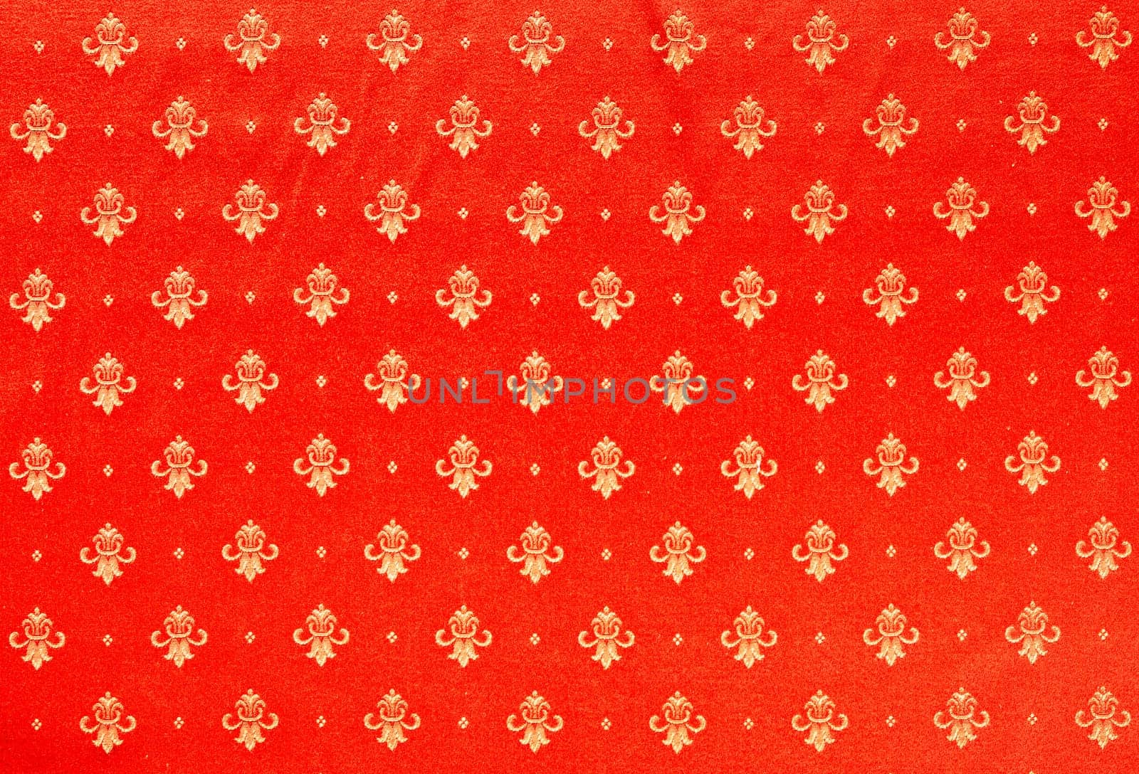 Abstract background of a heavy red brocade fabric with interwoven repeat design.