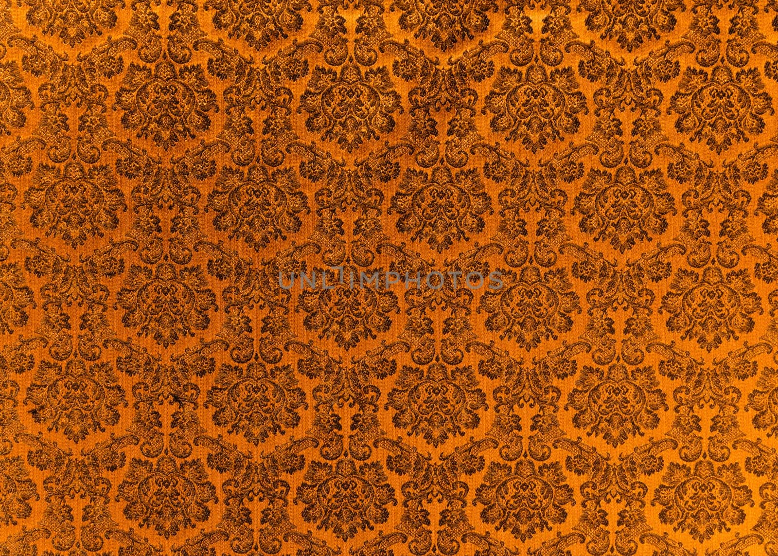 Abstract background of a heavy copper brocade fabric with interwoven repeat design.
