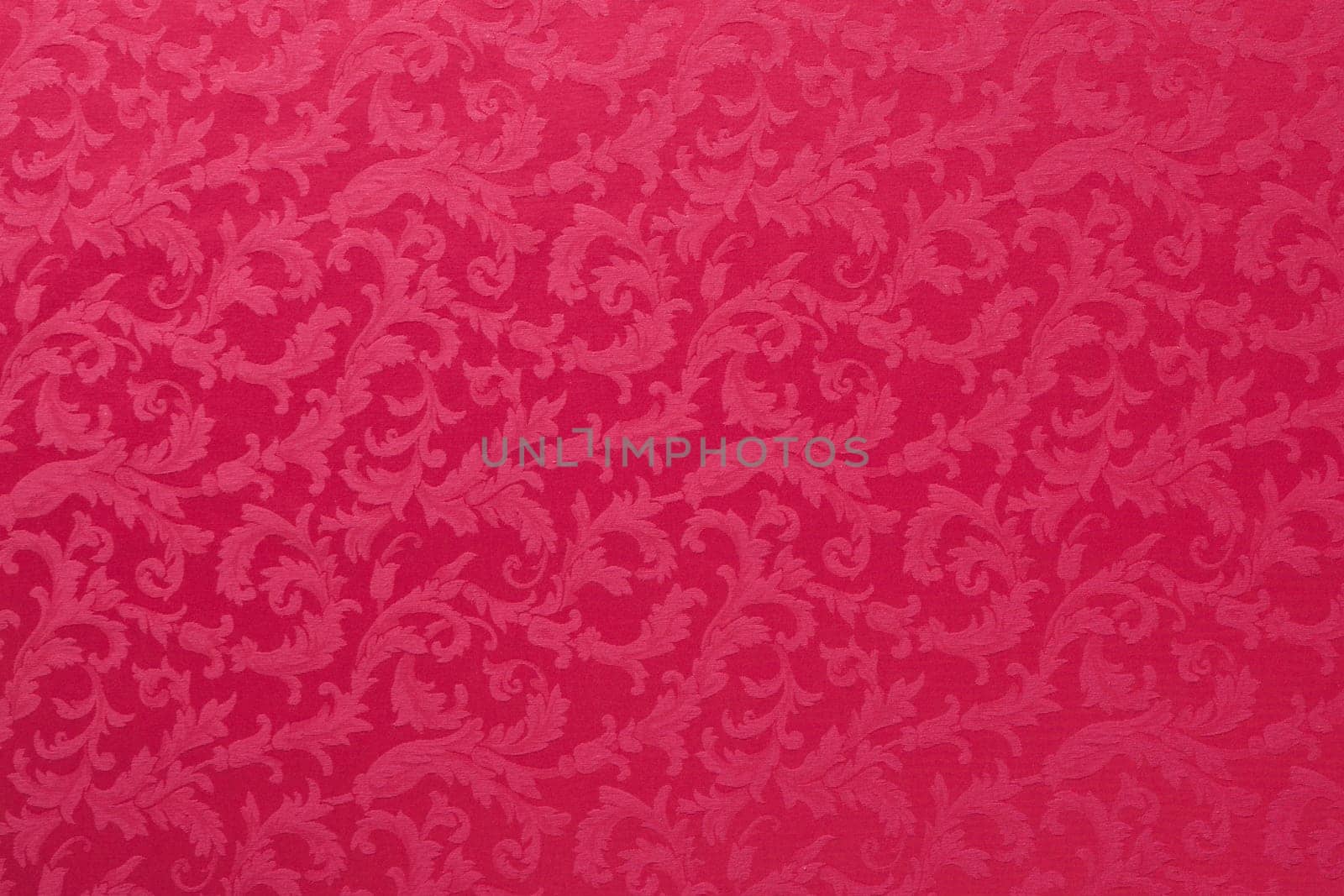 Abstract background of a heavy red brocade fabric with interwoven repeat design.