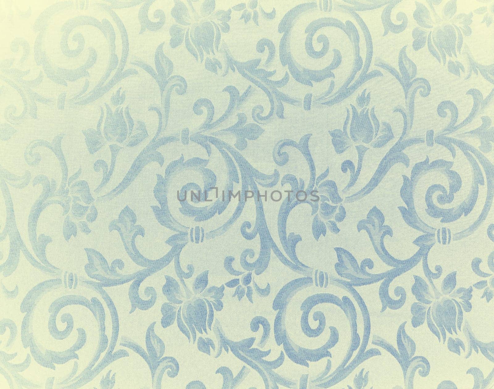 Abstract background of a heavy light yellow and blue brocade fabric with interwoven repeat design.