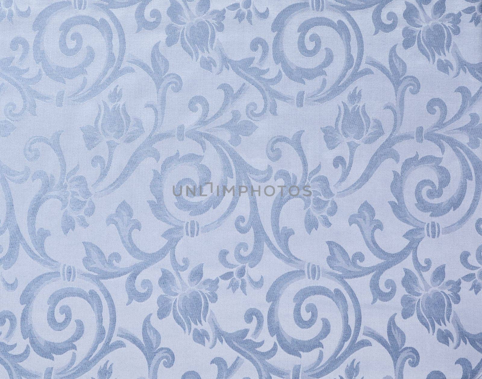 Abstract background of a heavy light blue brocade fabric with interwoven repeat design.