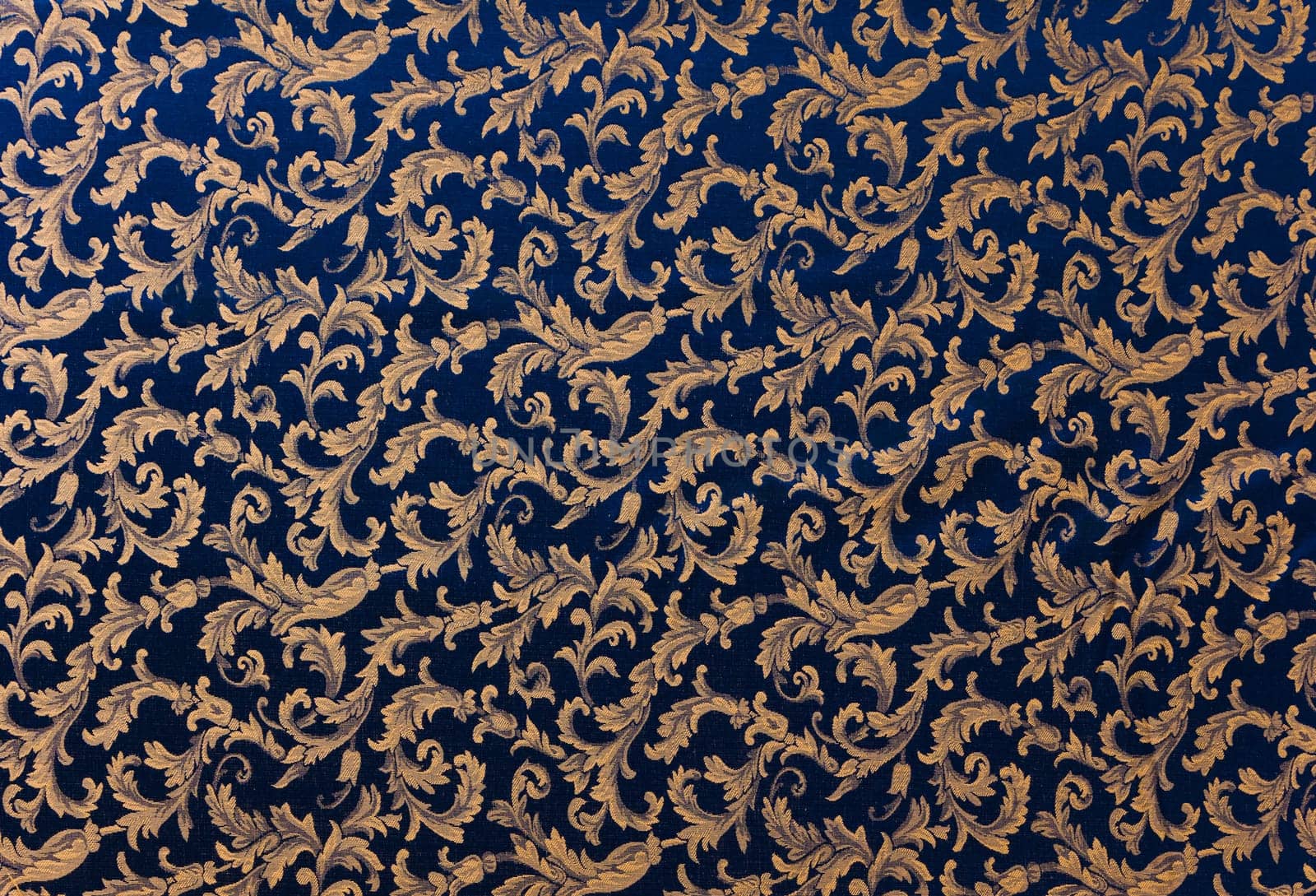 Abstract background of a heavy deep blue brocade fabric with interwoven repeat design.
