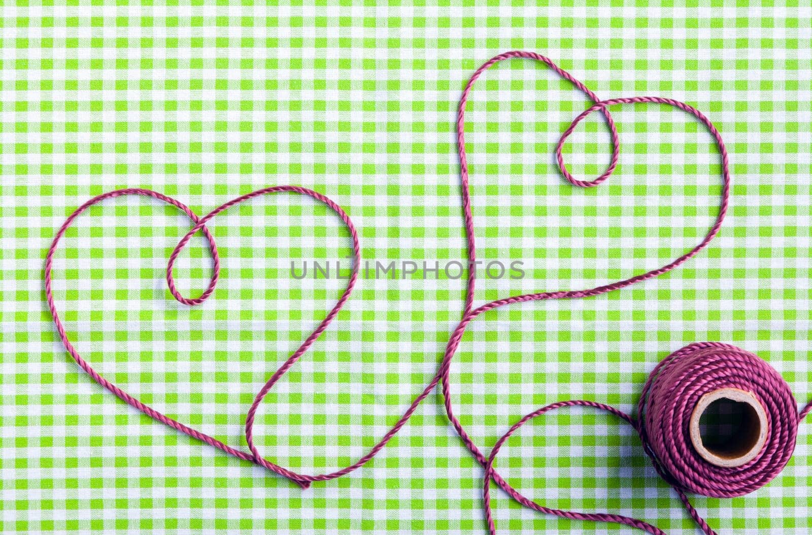Hearts drawn with purple thread through a tag over a checkered fabric pattern