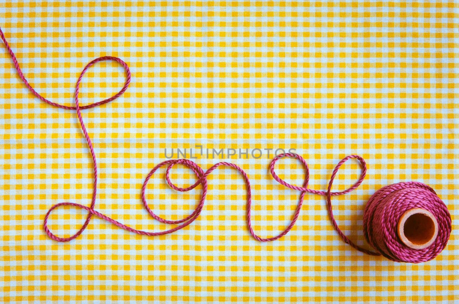 The word love drawn out with purple thread and a checked fabric background.