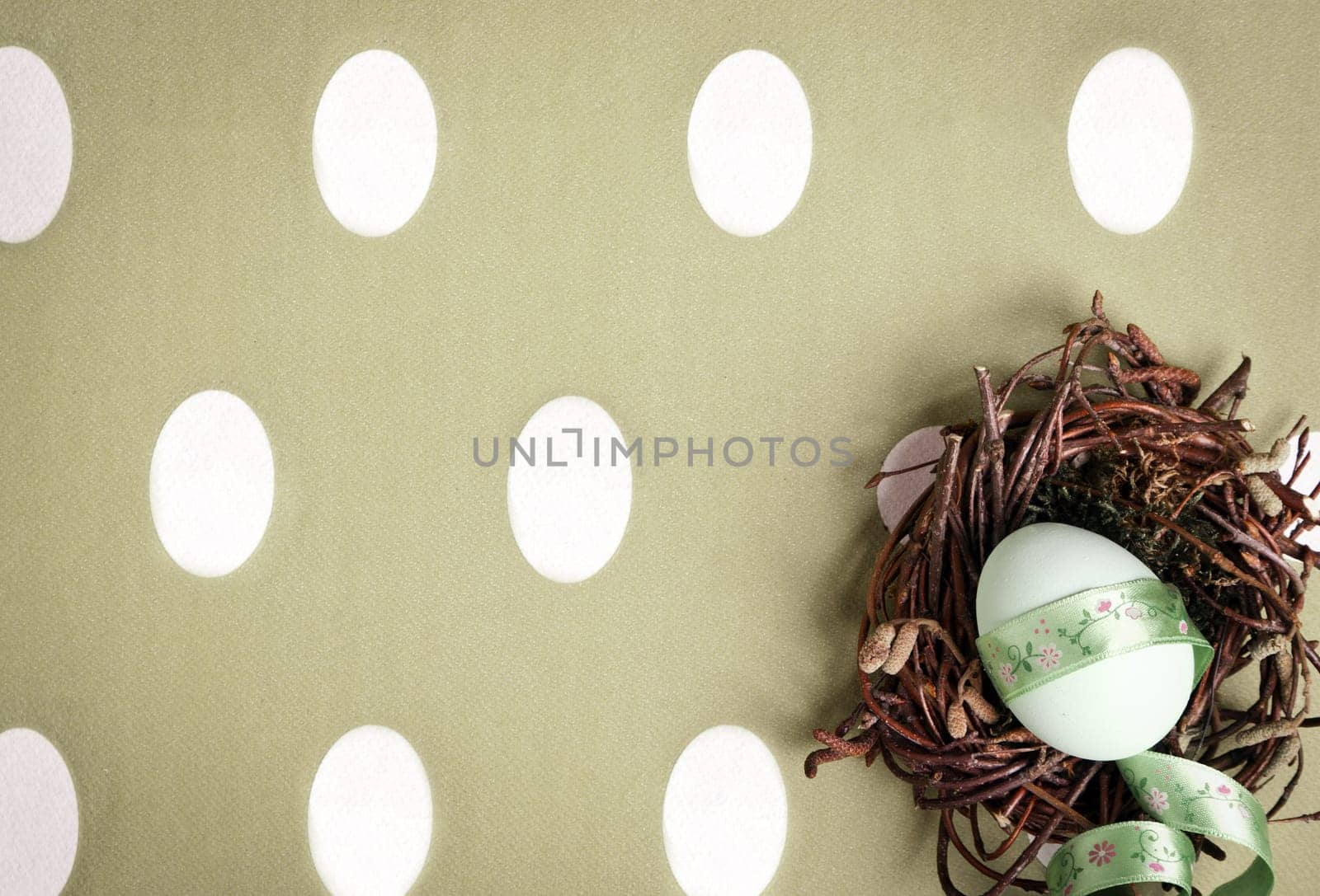 Small nest containing colored egg over a Easter concept background, with a bow