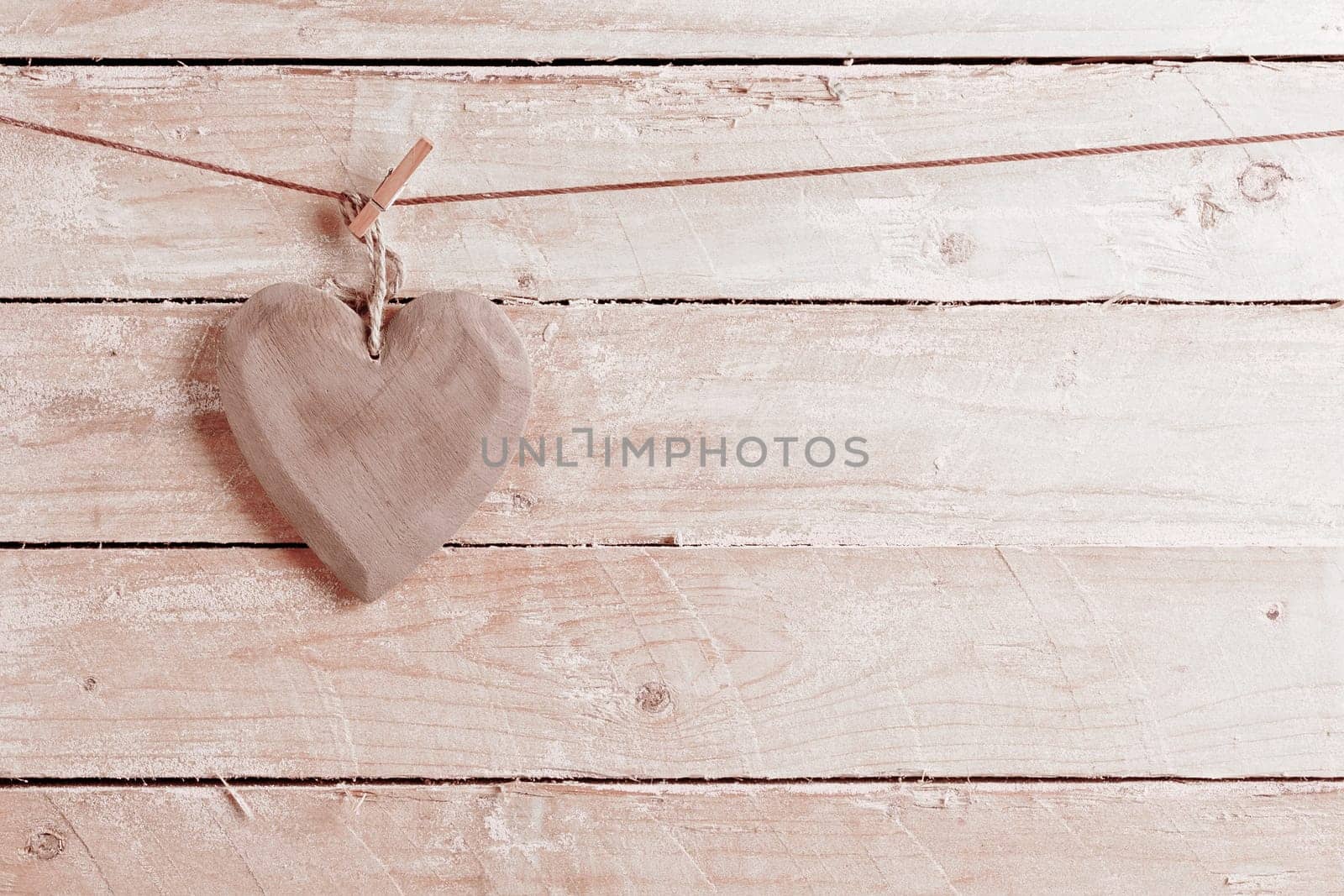 Quaint rustic wooden heart hanging from a peg against wooden boards with copyspace in a concept of love and romance