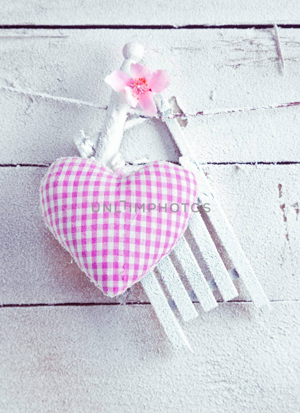A pretty romantic checked violet needlework heart with flower hanging on painted white boards