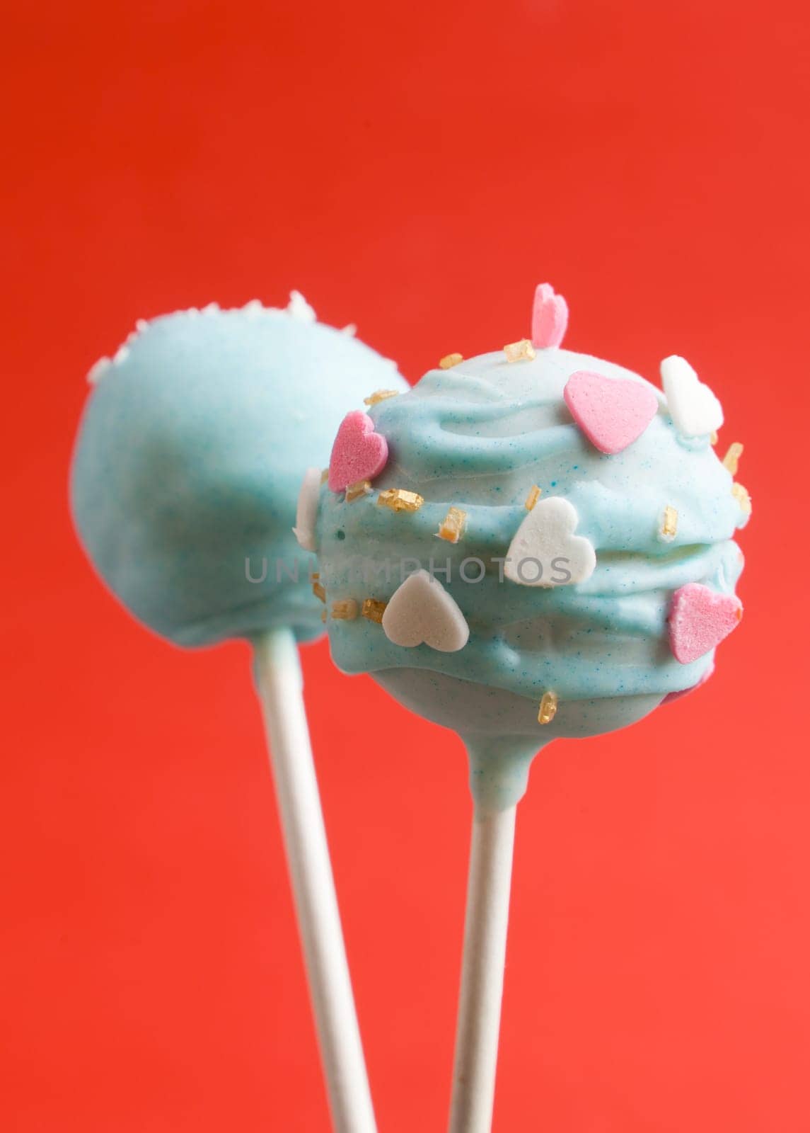 Cake pops with heart shaped candy on red background