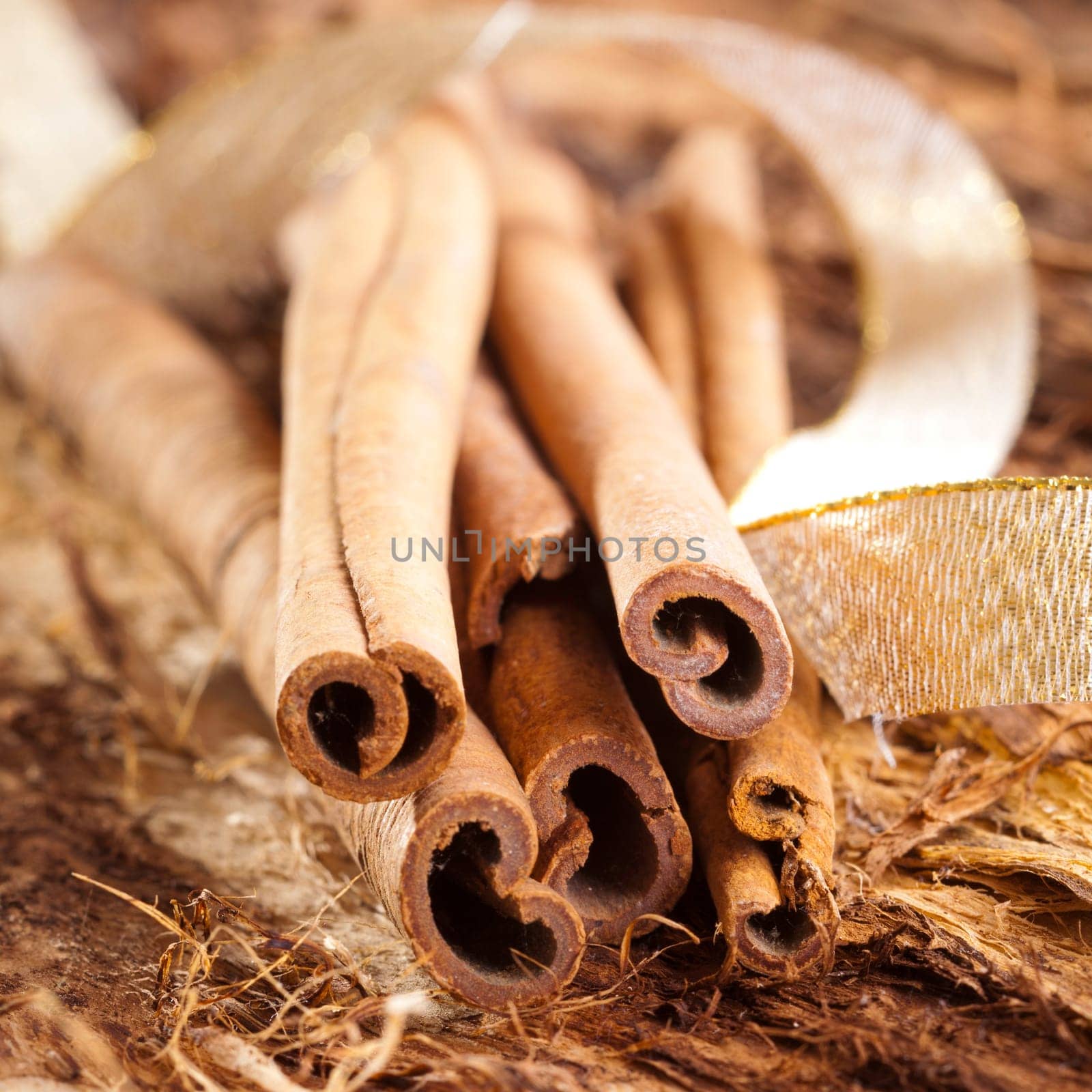 a few cinnamon sticks on wooden background an a golden bow