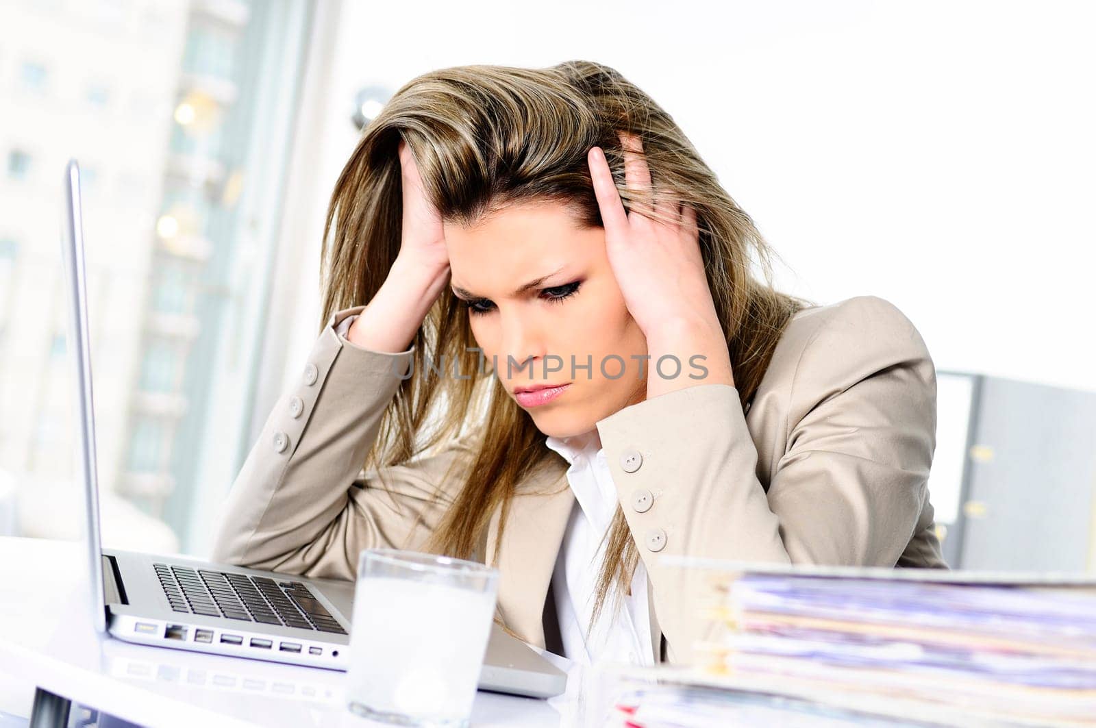 young woman stressed at work, taking an aspirin cahet