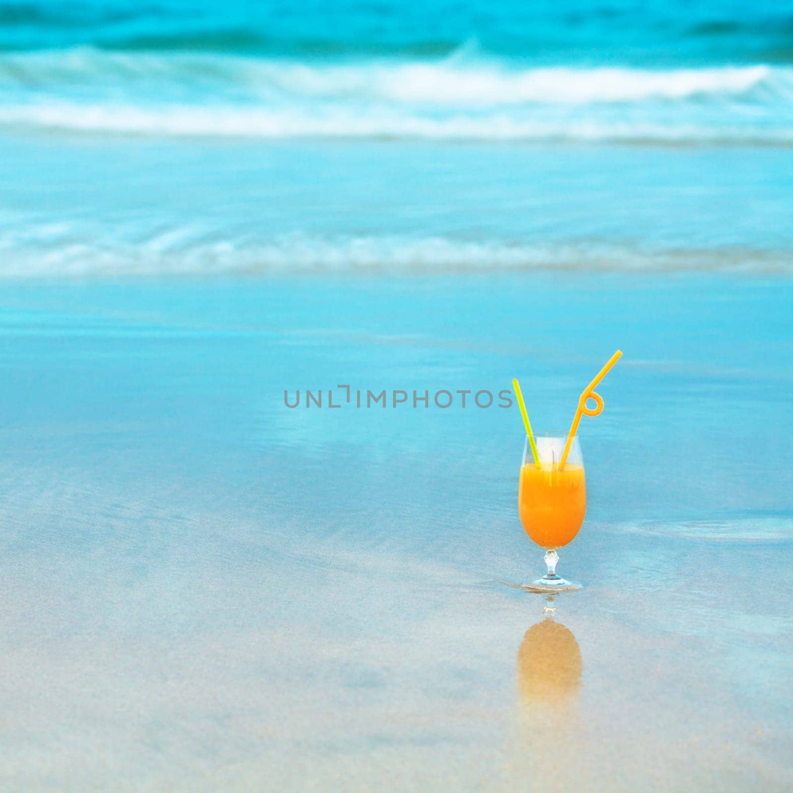 Glass of orange juice on the beach