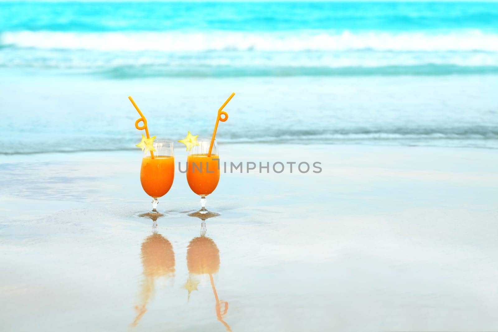 Two glasses of orange juice on tropical beach