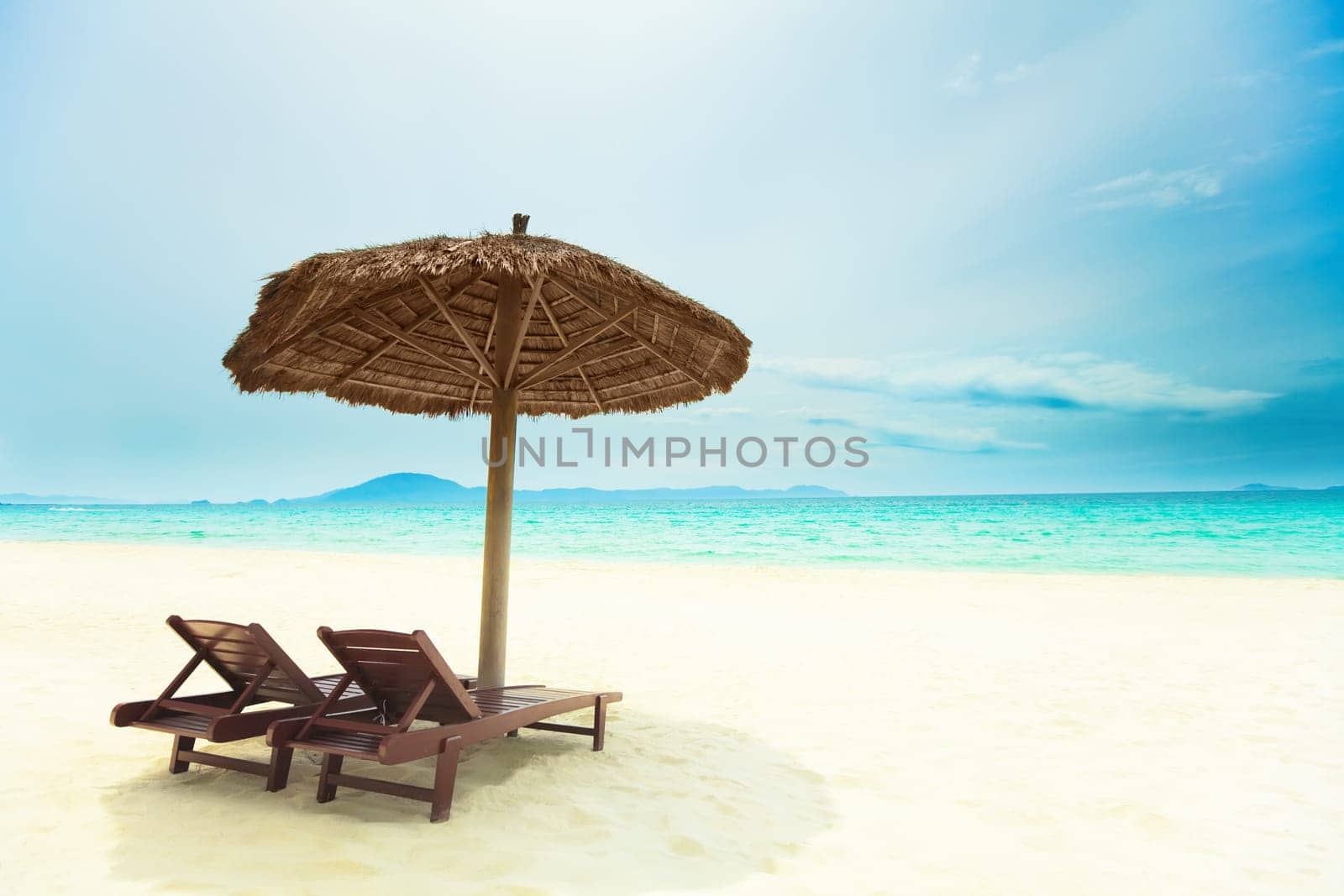 Sandy tropical beach with deck chairs in sunny day
