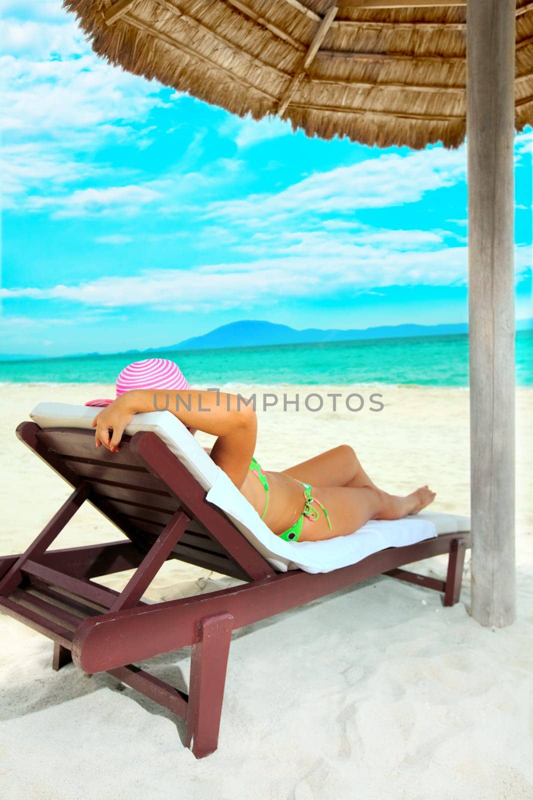 Young woman sunbathing on the chair near the ocean