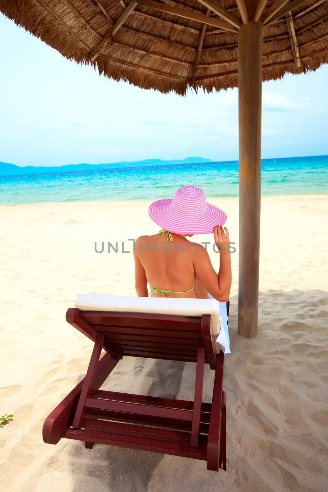 Young woman sunbathing on the chair near the ocean