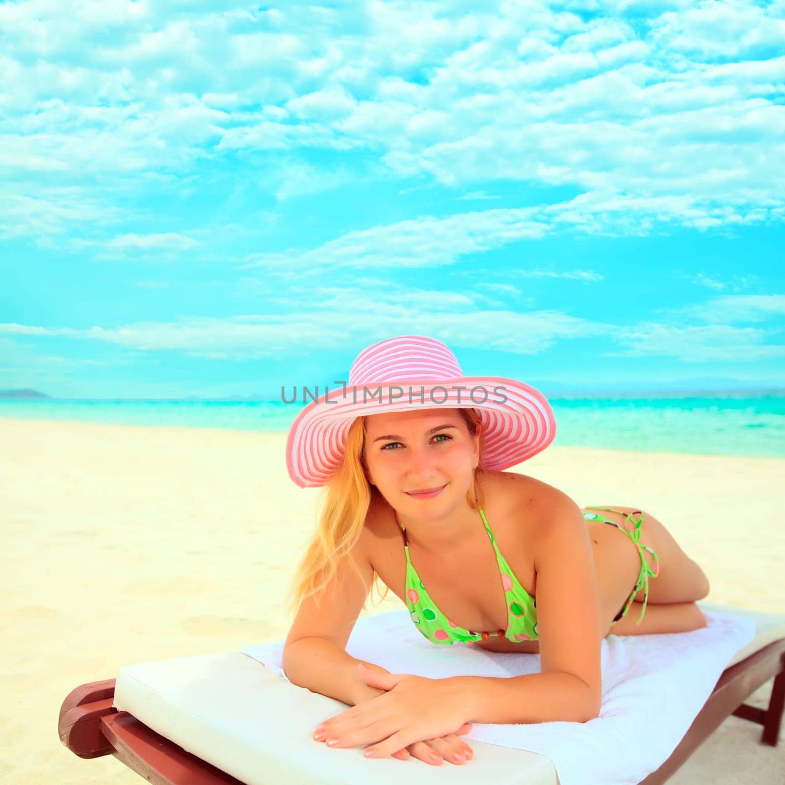 Young woman sunbathing on the chair near the ocean
