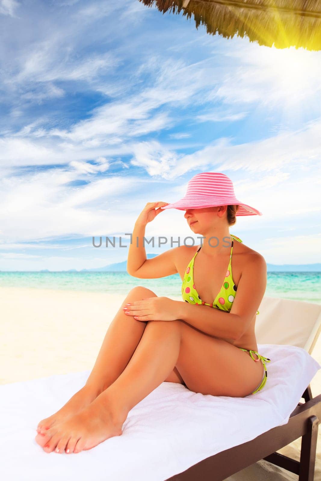 Young woman sunbathing on the chair near the ocean