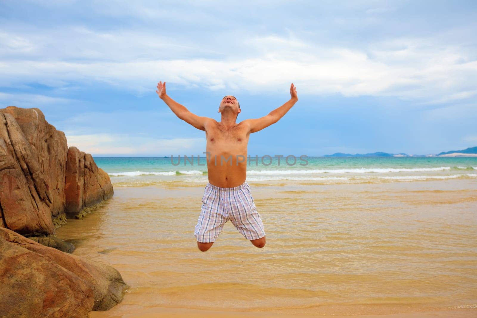Young man jumping on the tropical beach