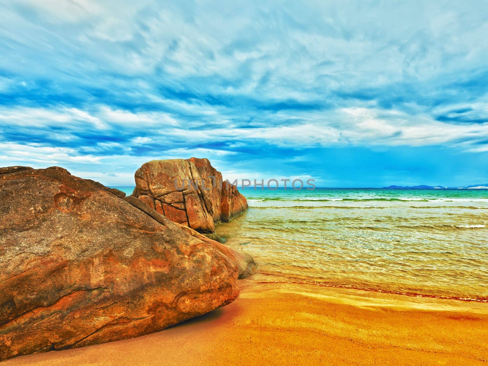 Tropical beach with rock and cloudy sky