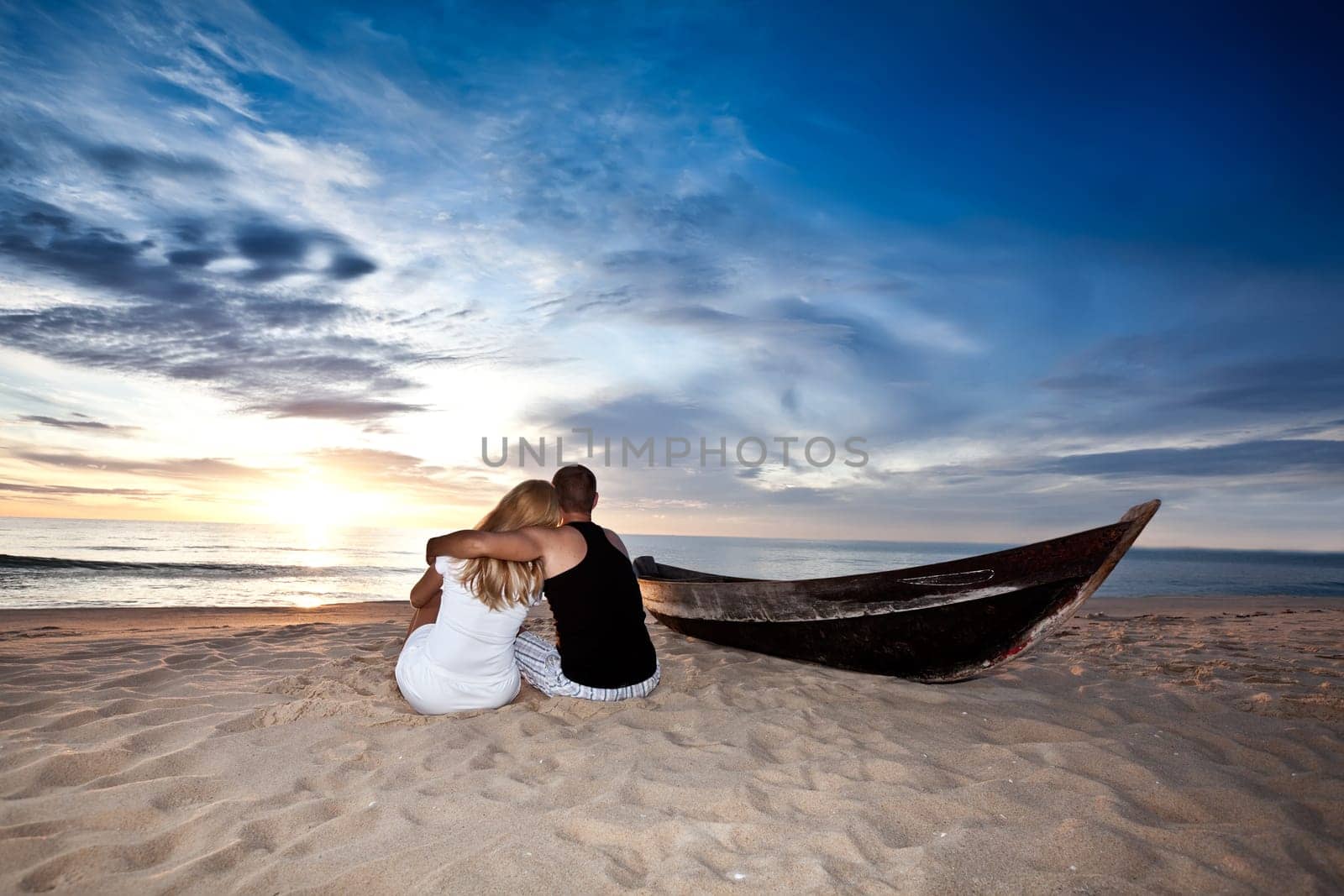 Romantic couple and boat on the beach at sunrise time