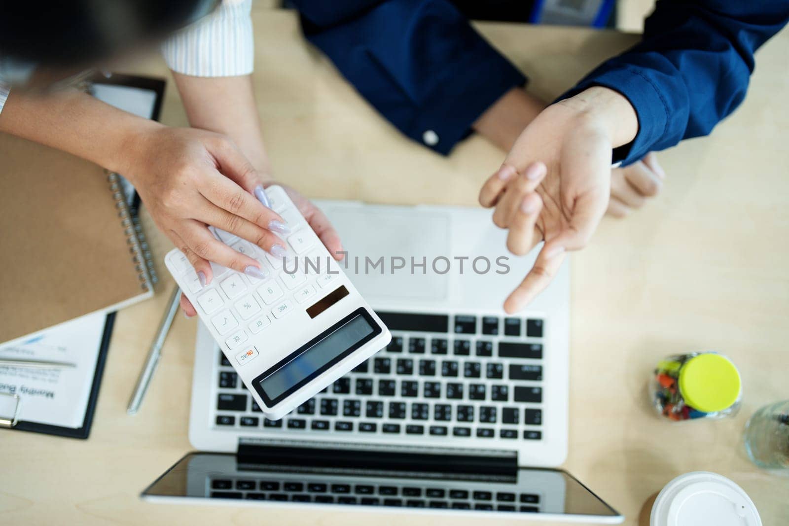 Two business people meeting to talking or discuss marketing work in workplace using paperwork, calculator, computer to work by Manastrong