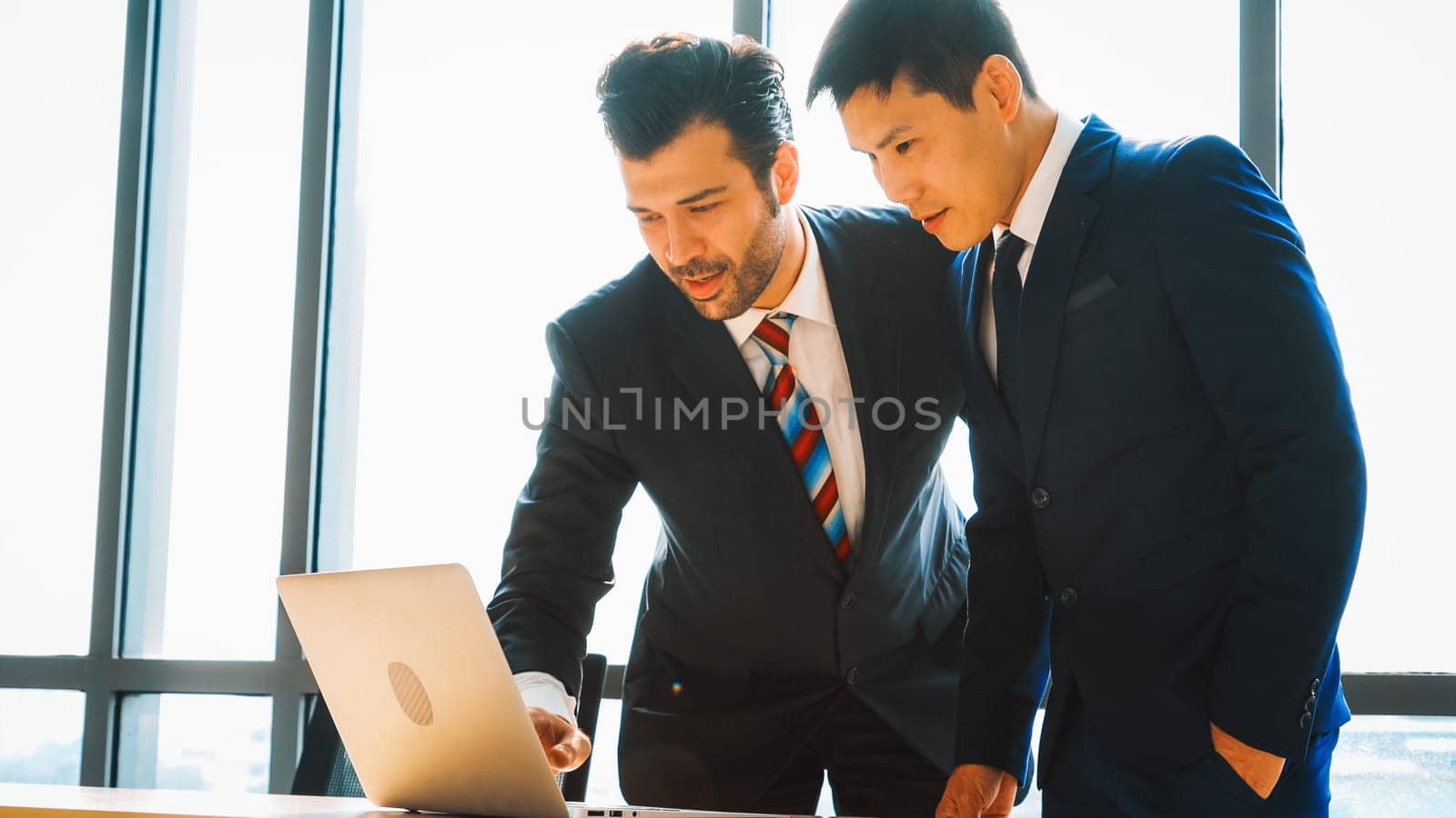 Two business people talk project strategy at office meeting room. Businessman discuss project planning with colleague at modern workplace while having conversation and advice on financial report. Jivy