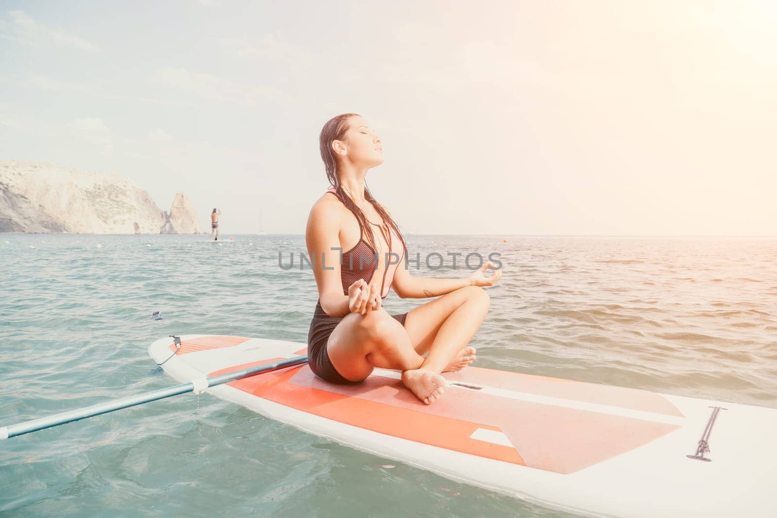 Woman sup yoga. Happy young sporty woman practising yoga pilates on paddle sup surfboard. Female stretching doing workout on sea water. Modern individual female outdoor summer sport activity